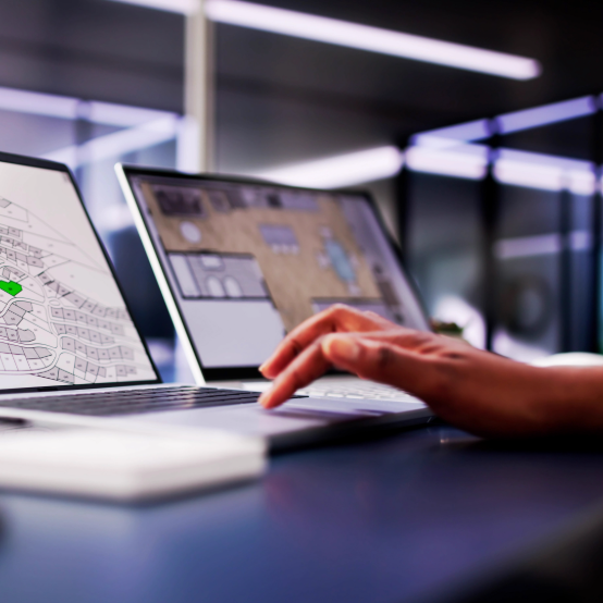 A hand touches a laptop with a GIS project onscreen