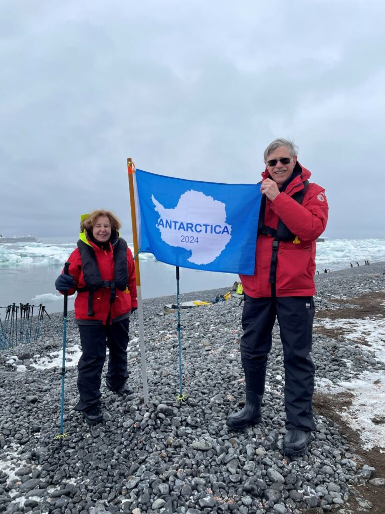 Carl and Sandra Lindstrom stand with a flag on Antarctica