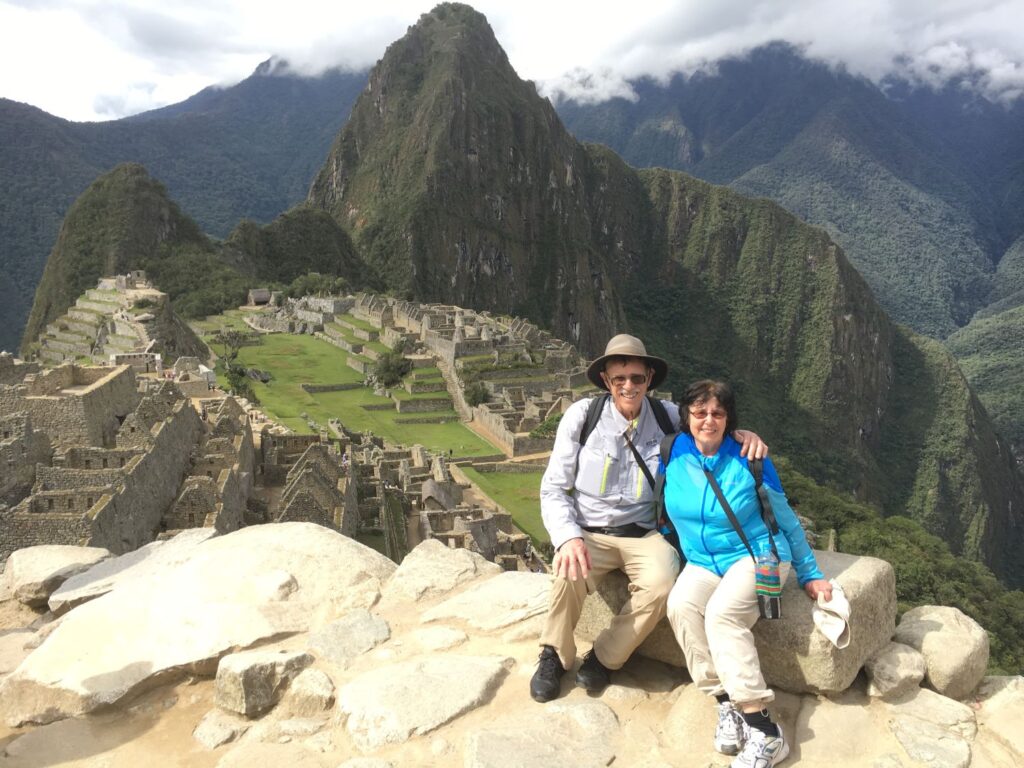 Carl and Sandra Lindstrom sit on a mountain with Machu Picchu in the background