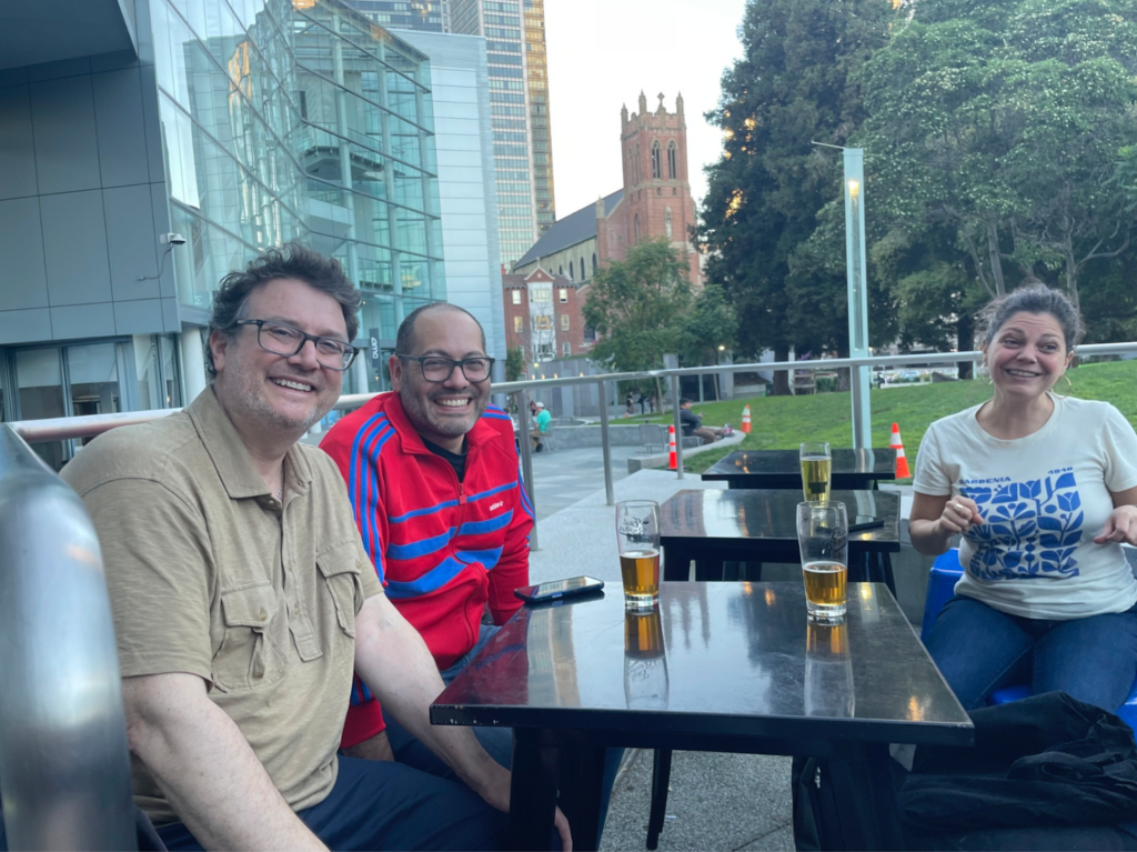 Colleagues share beers in the outdoor seating area of East Brother Beer Co. at the 2026 AAG party.