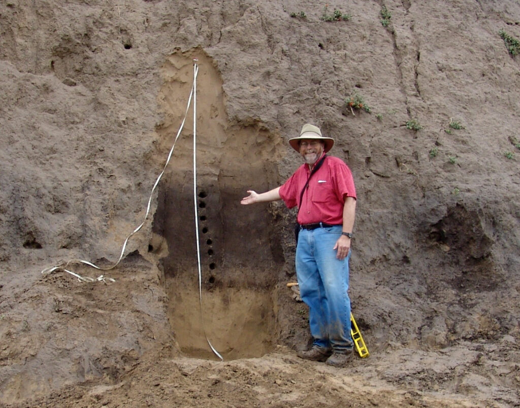 Joe Mason poses next to a wall of rock and dirt