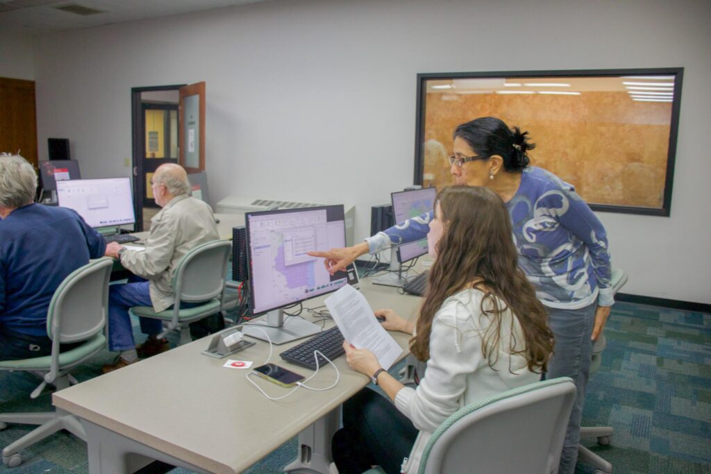A woman points to a computer screen while another woman looks at the screen.