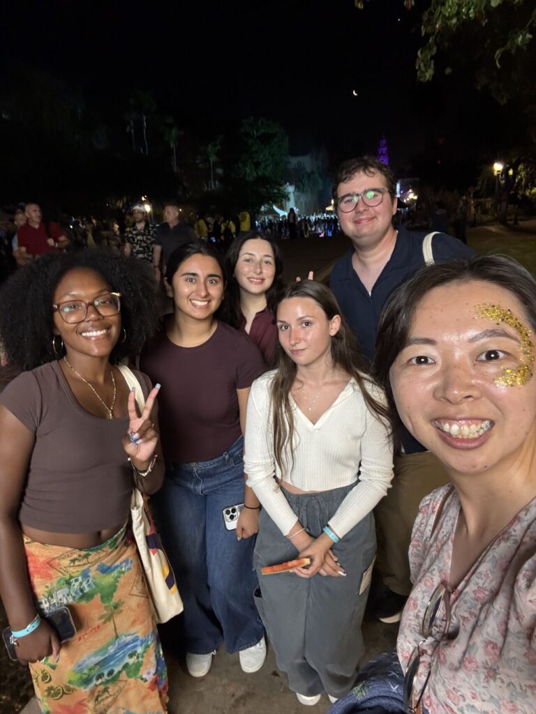 A group of young people stands in a crowded outdoor space, smiling for the camera.
