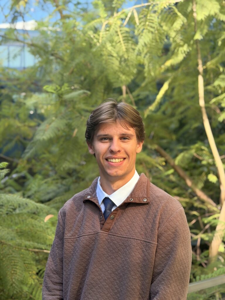 Sean Cervenka stands in front of greenery