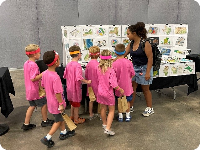A group of children gathers around a table full of LEGO maps