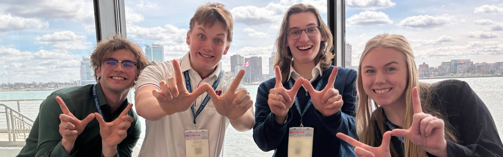 Four undergrad Geography students pose with their hands making Ws