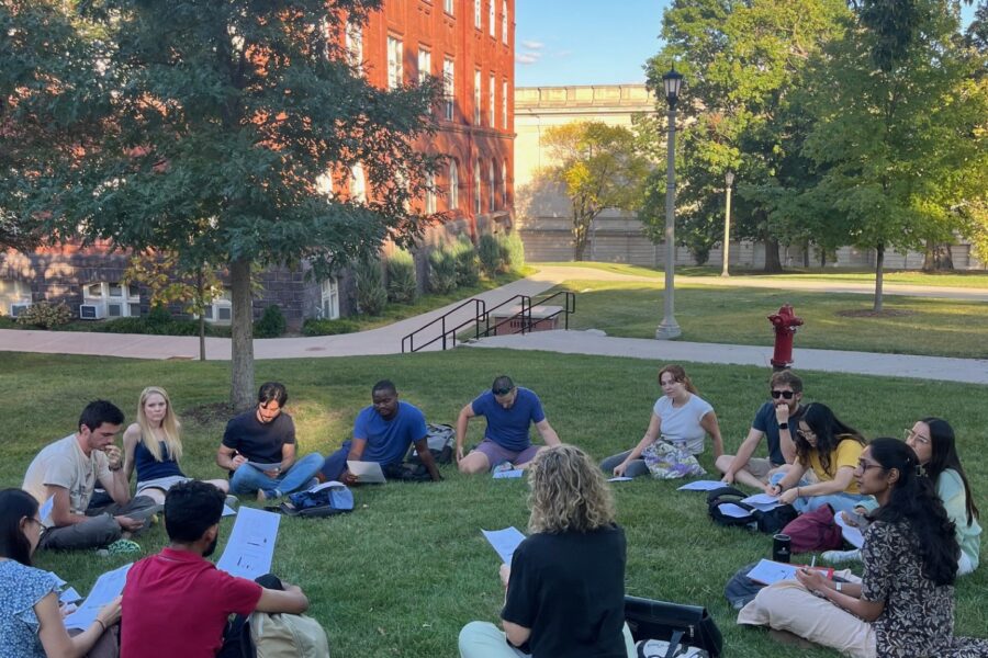 A geography class meeting in the grass outside Science Hall